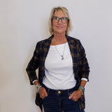 Woman wearing a plaid jacket, white shirt, and blue jeans against a plain background