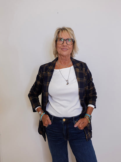 Woman wearing a plaid jacket, white shirt, and blue jeans against a plain background