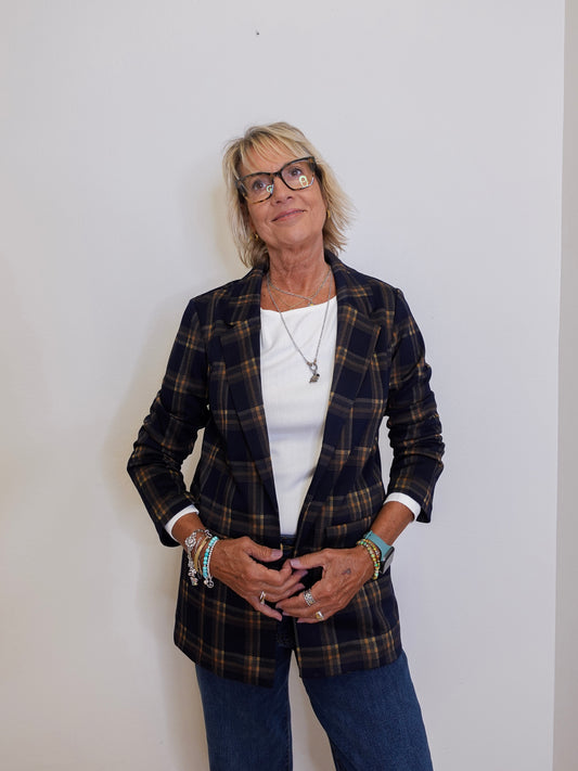 Woman wearing a plaid blazer over a white shirt with a plain background