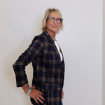 Person wearing a plaid blazer and glasses against a plain background