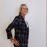 Person wearing a plaid blazer and glasses against a plain background