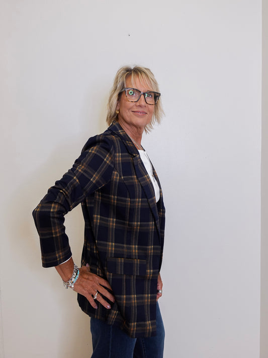 Person wearing a plaid blazer and glasses against a plain background