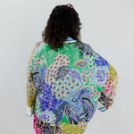 Person wearing a colorful patterned jacket on a plain background