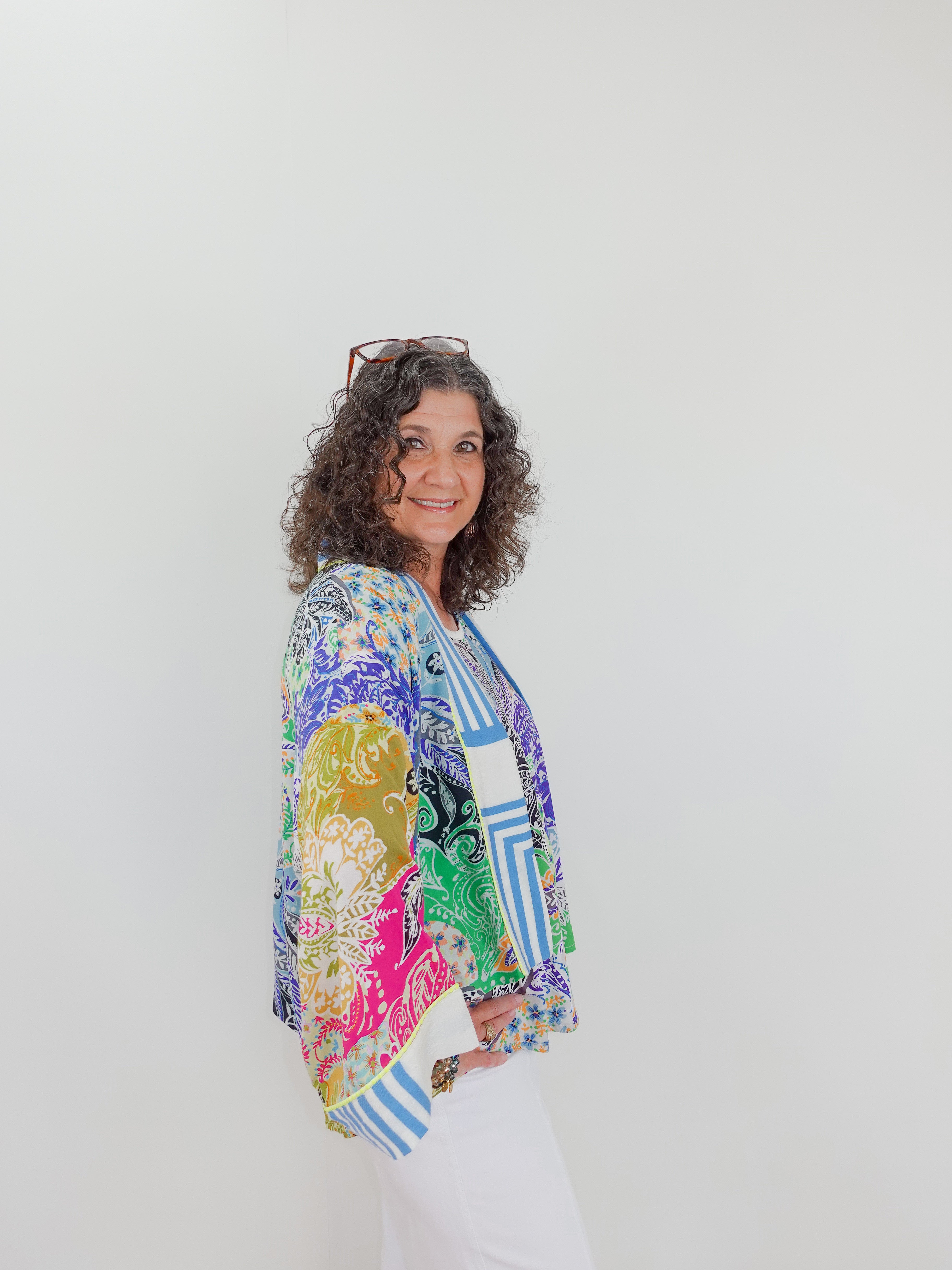 Woman wearing a colorful patterned shirt against a white background
