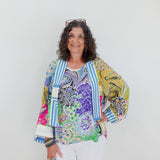 Woman wearing a colorful patterned jacket against a white background