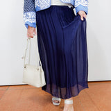 White textured blouse styled with a navy silk foldover waist skirt and blue patterned jacket.
