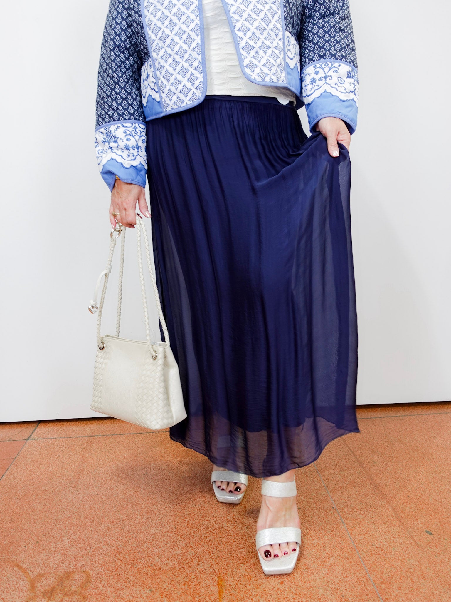 White textured blouse styled with a navy silk foldover waist skirt and blue patterned jacket.