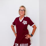 Woman wearing a maroon dress with 'AGGIES' text against a white background