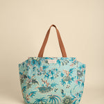 Floral-patterned tote bag with brown handle on beige background