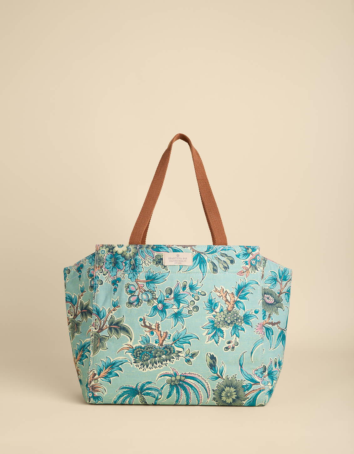 Floral-patterned tote bag with brown handle on beige background