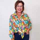 Woman wearing a colorful patterned shirt and glasses against a white background