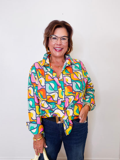 Woman wearing a colorful patterned shirt and glasses against a white background