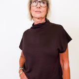 Person wearing a brown mock neck shirt and glasses on a white background