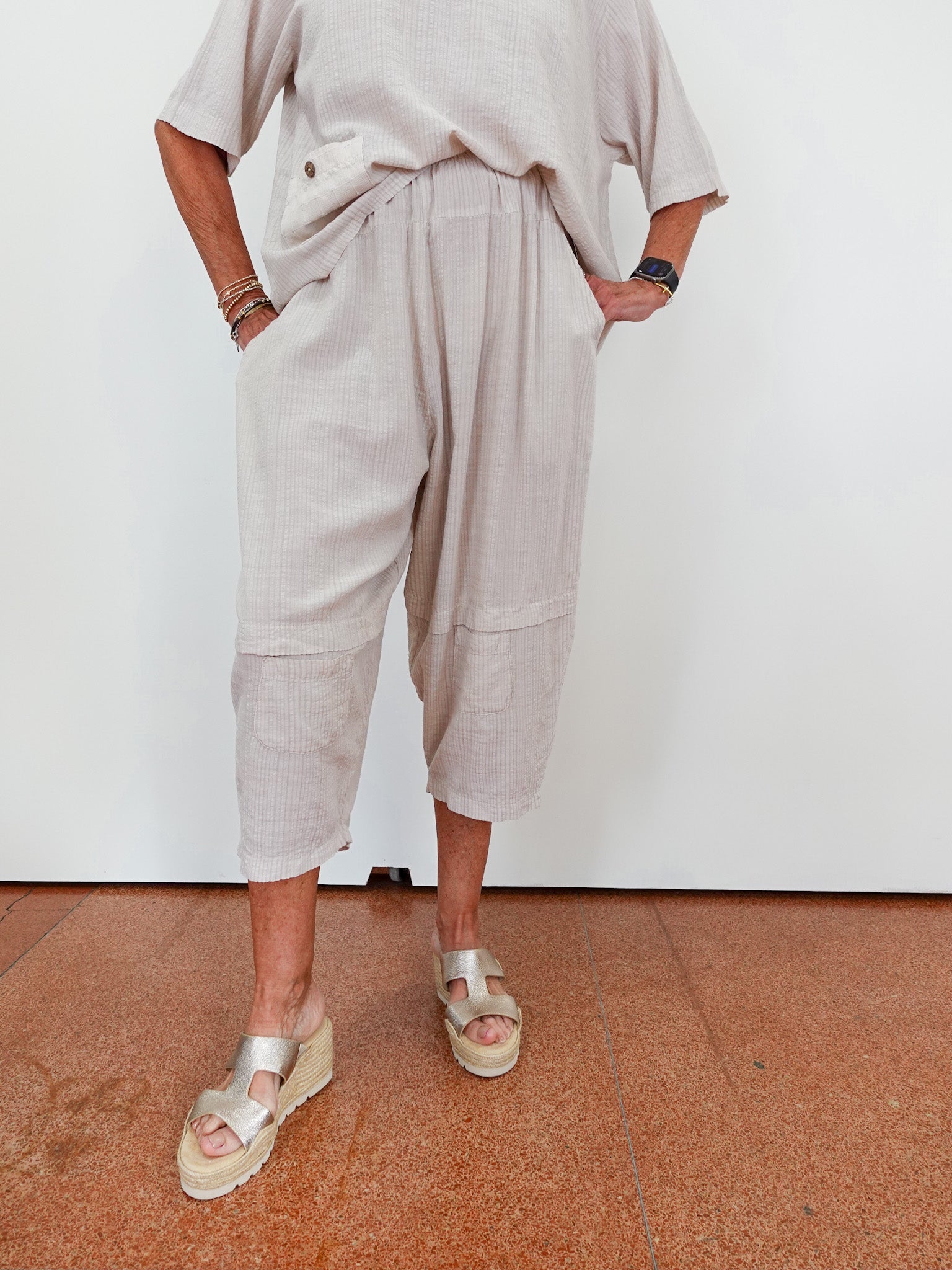 Person wearing beige pants and sandals on a white background