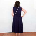 Person wearing a navy blue dress standing against a white wall.