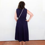 Person wearing a navy blue dress standing against a white wall.