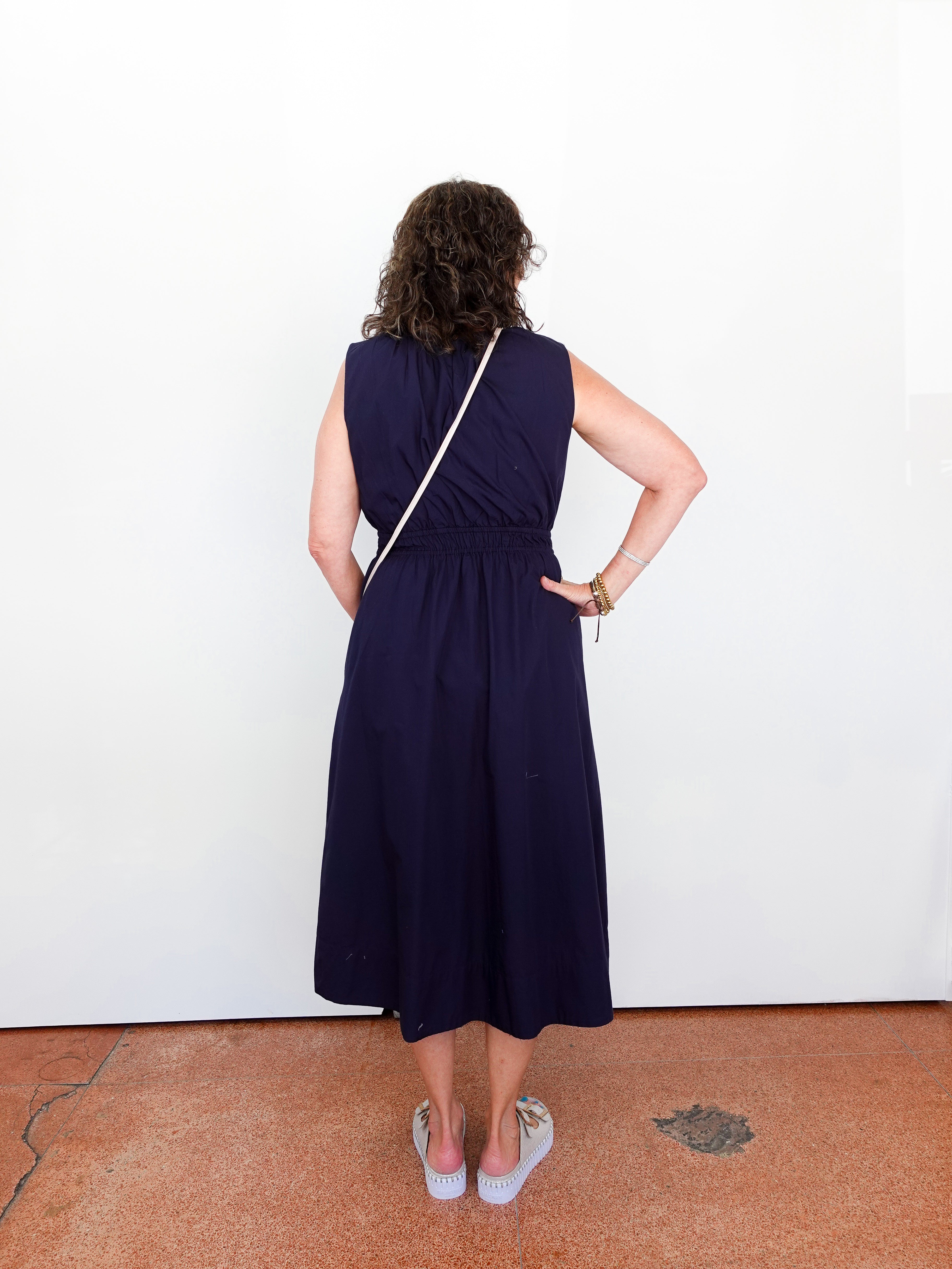 Person wearing a navy blue dress standing against a white wall.