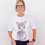 Person wearing a white t-shirt with a rabbit graphic and crown design on a plain background