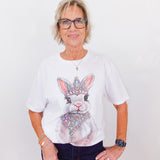 Person wearing a white t-shirt with a rabbit graphic and crown design on a plain background