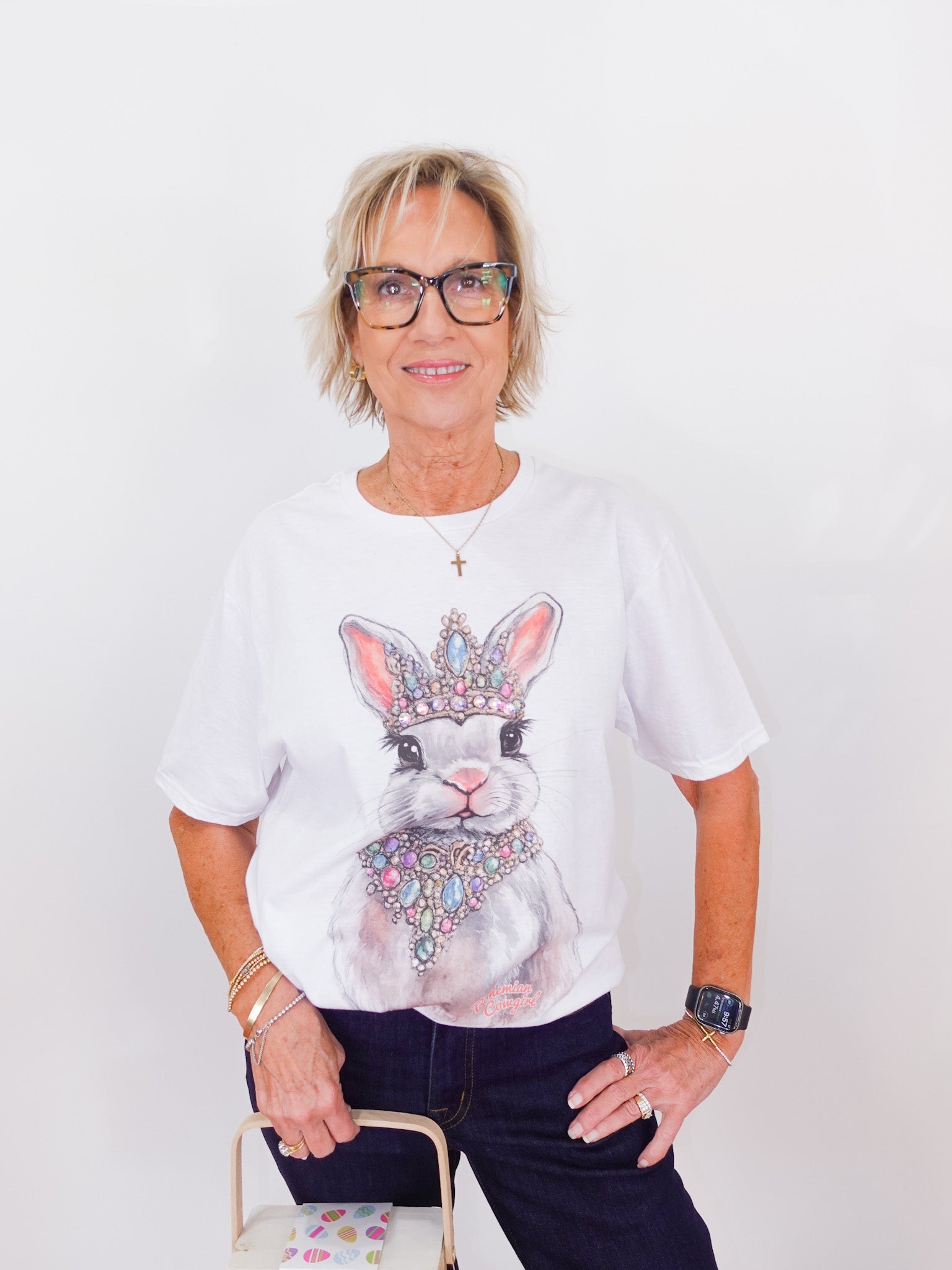 Person wearing a white t-shirt with a rabbit graphic and crown design on a plain background