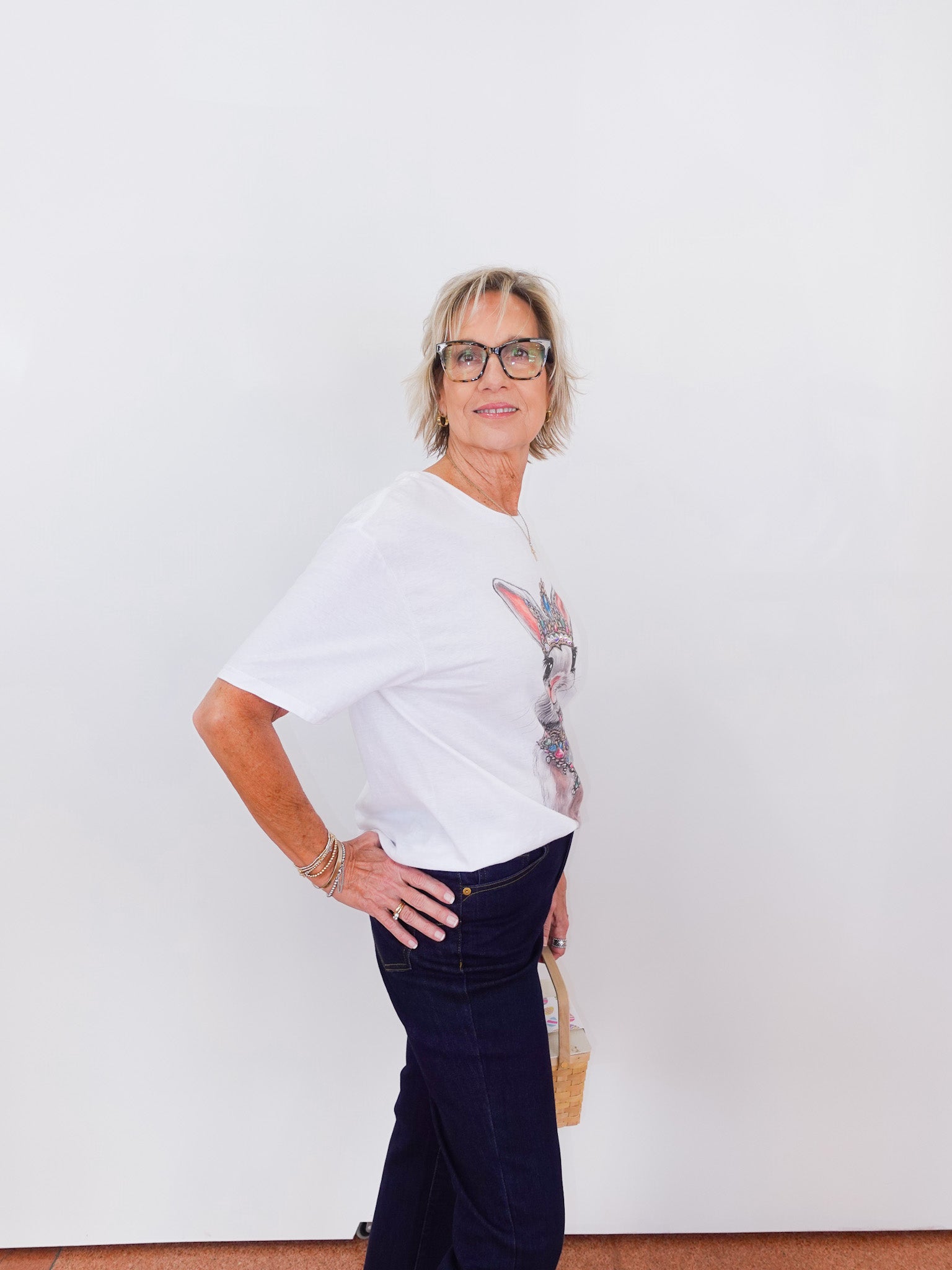 Person wearing a white top with floral sleeves and dark pants against a white background