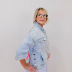 Person wearing a light blue denim jacket against a plain background