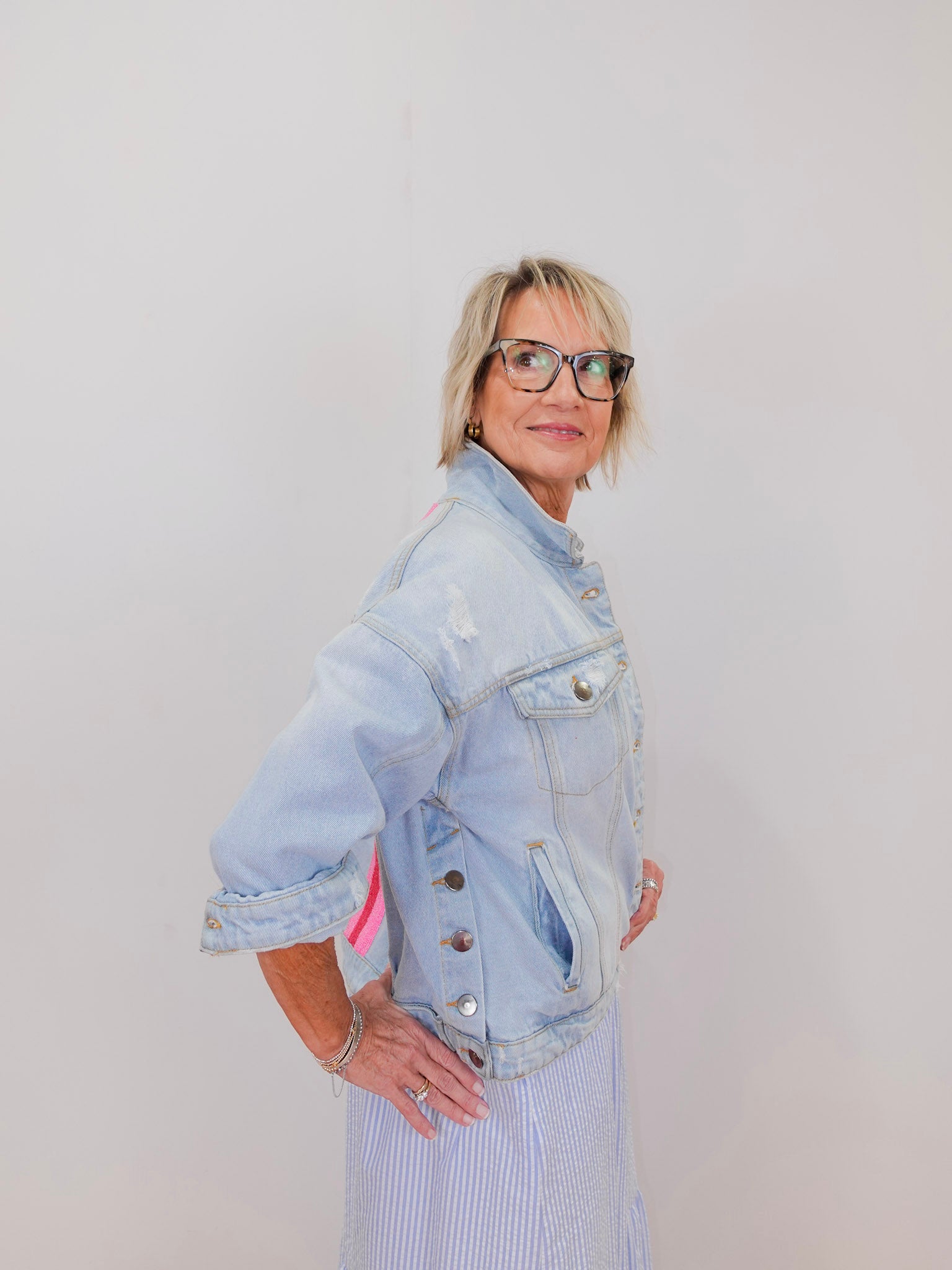 Person wearing a light blue denim jacket against a plain background