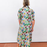 Person wearing a colorful butterfly-patterned dress against a white wall.