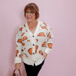 Woman wearing a patterned cardigan against a pink wall