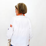 Person wearing a white shirt with colorful designs on a plain background