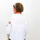 Person wearing a white shirt with colorful designs on a plain background