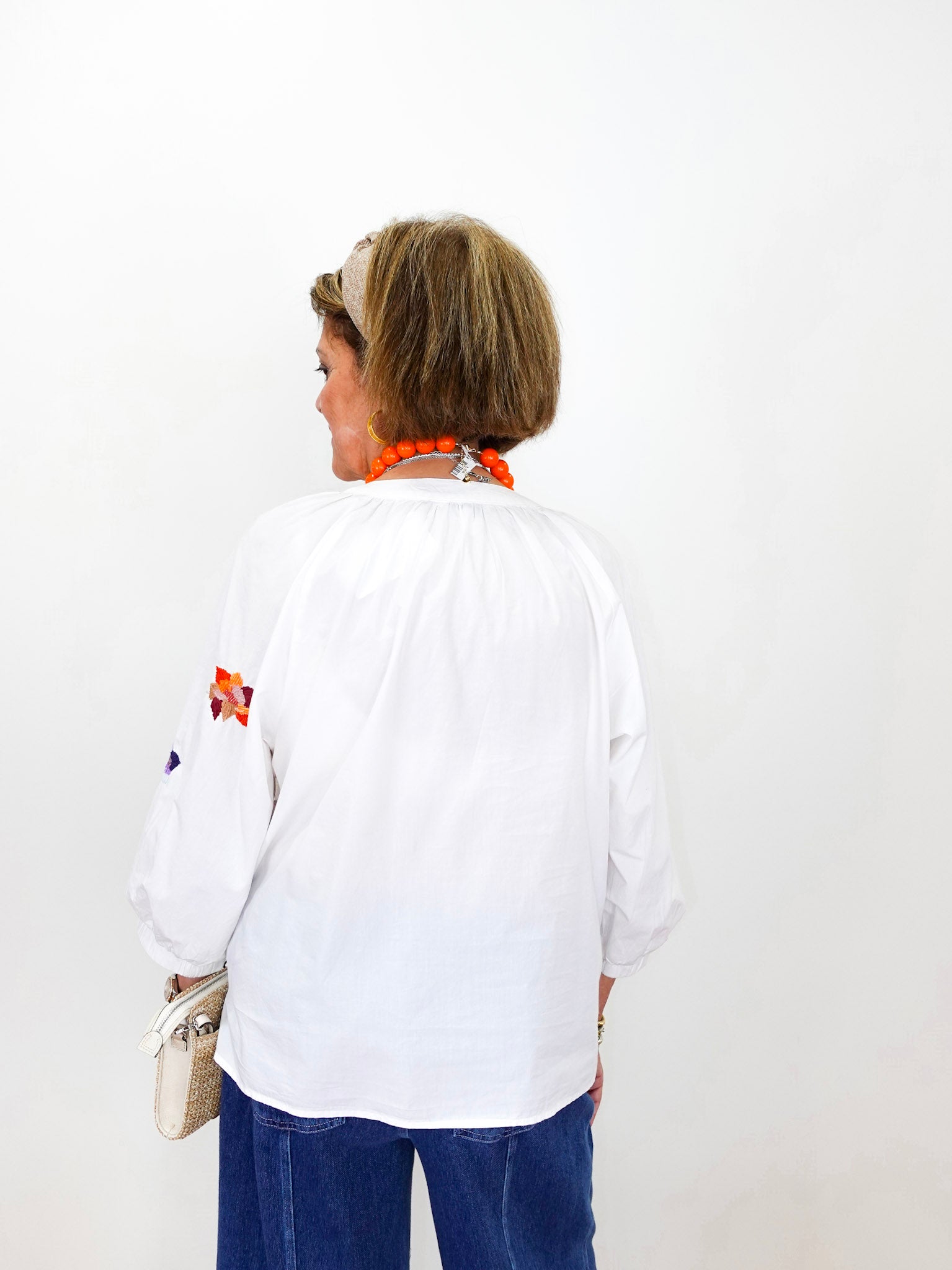 Person wearing a white shirt with colorful designs on a plain background
