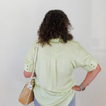 Person wearing a light green shirt and blue jeans against a white background