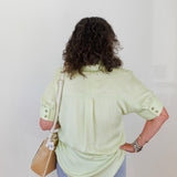 Person wearing a light green shirt and blue jeans against a white background