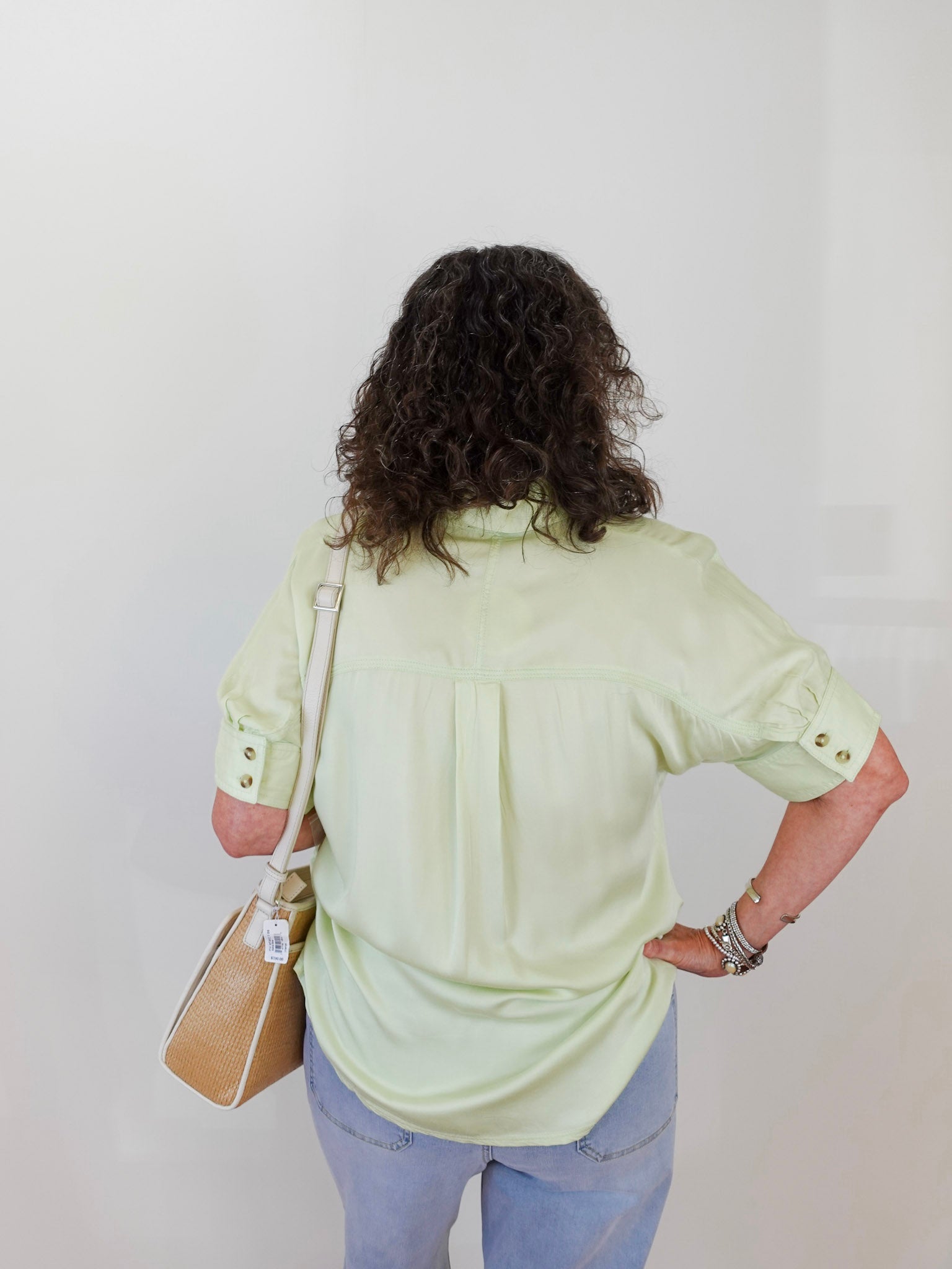 Person wearing a light green shirt and blue jeans against a white background