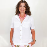 Woman wearing a white shirt and floral skirt with a pink necklace against a white background