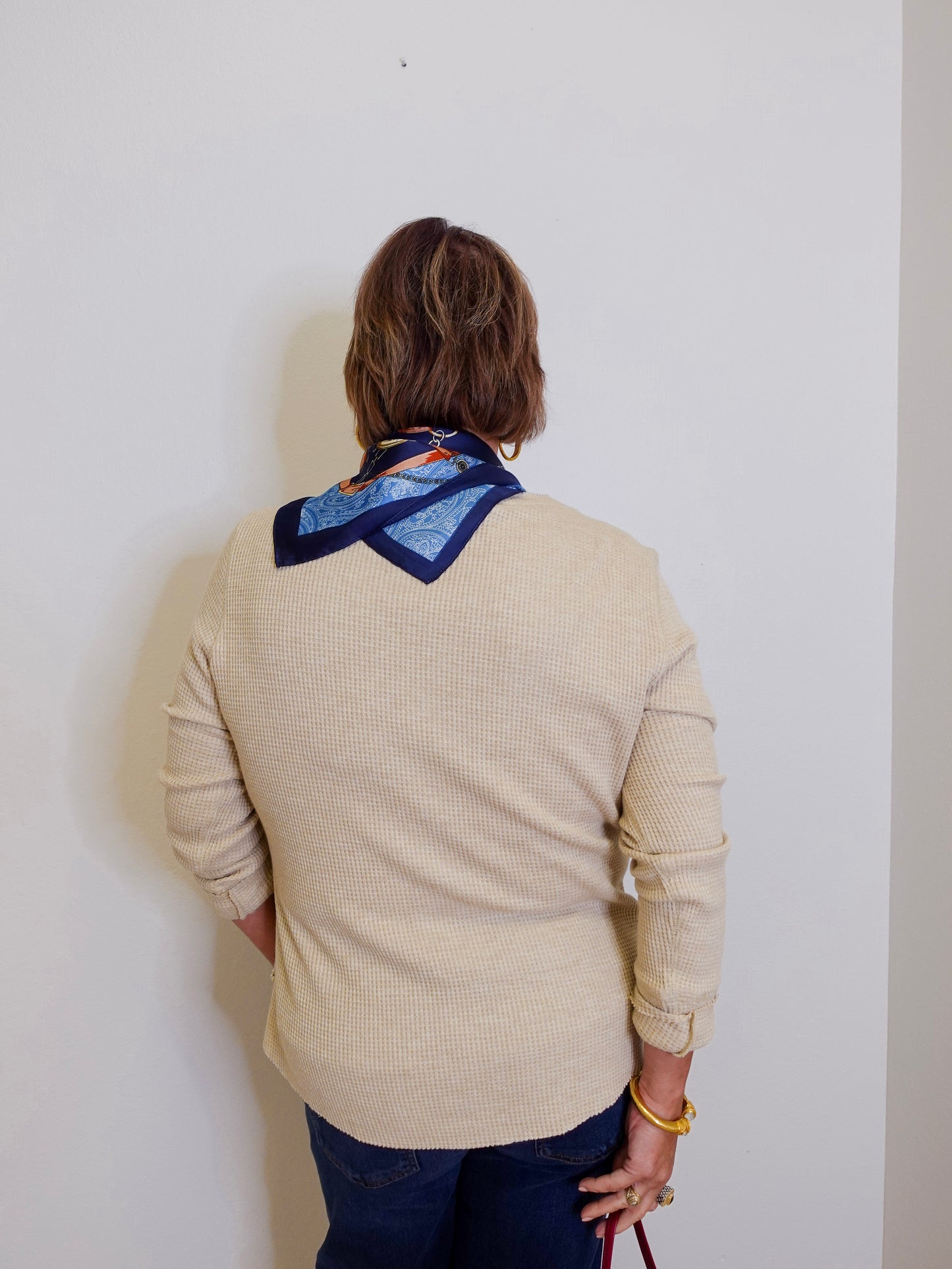 woman wearing a tan waffle knit blouse against a white background. 