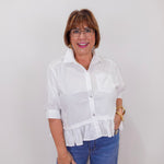 Woman wearing a white blouse and blue jeans against a plain background