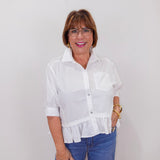 Woman wearing a white blouse and blue jeans against a plain background