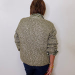 Person wearing a patterned jacket against a white wall