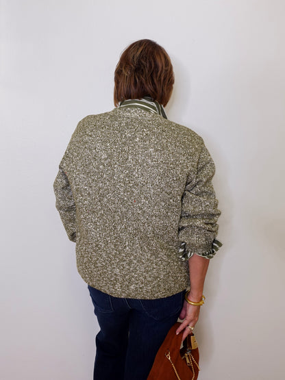 Person wearing a patterned jacket against a white wall