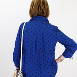 Person wearing a blue polka dot shirt with a white background