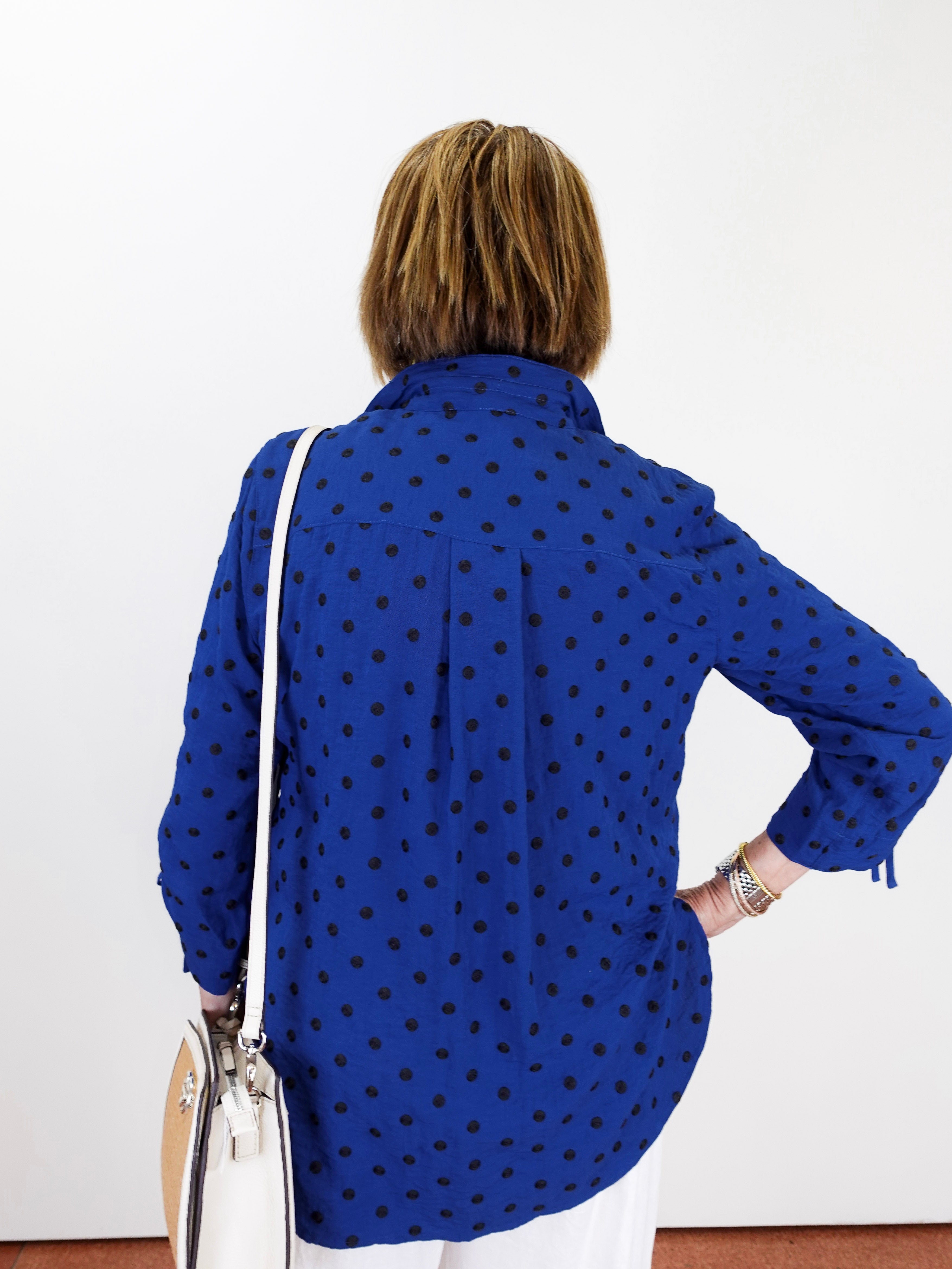 Person wearing a blue polka dot shirt with a white background