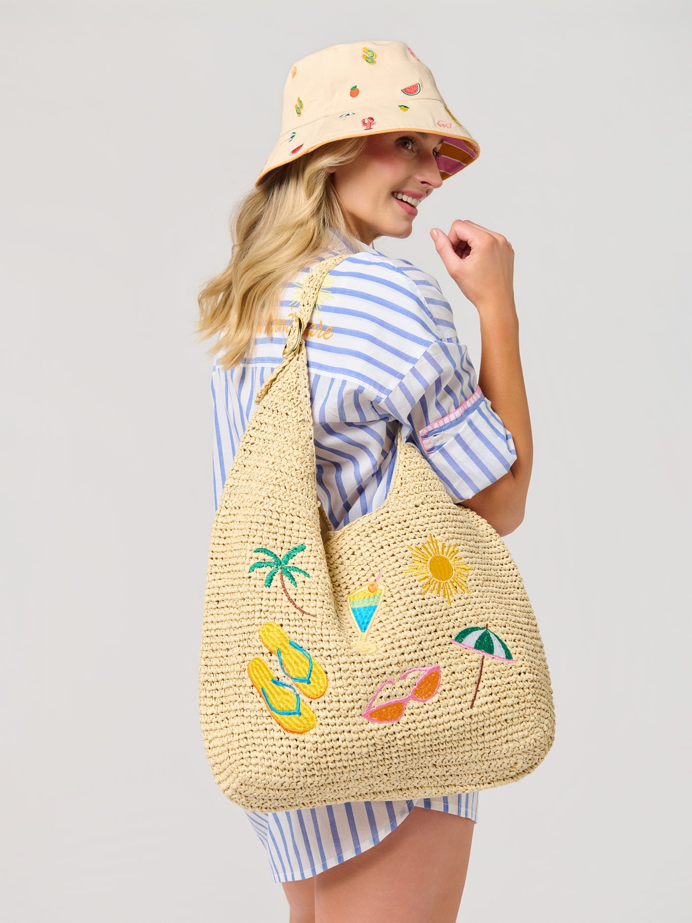 Woman wearing a straw bag with summer-themed embroidery on a plain background