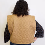 Person wearing a beige quilted vest with a white background