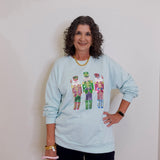 Woman wearing a light blue sweatshirt with colorful designs on a plain background