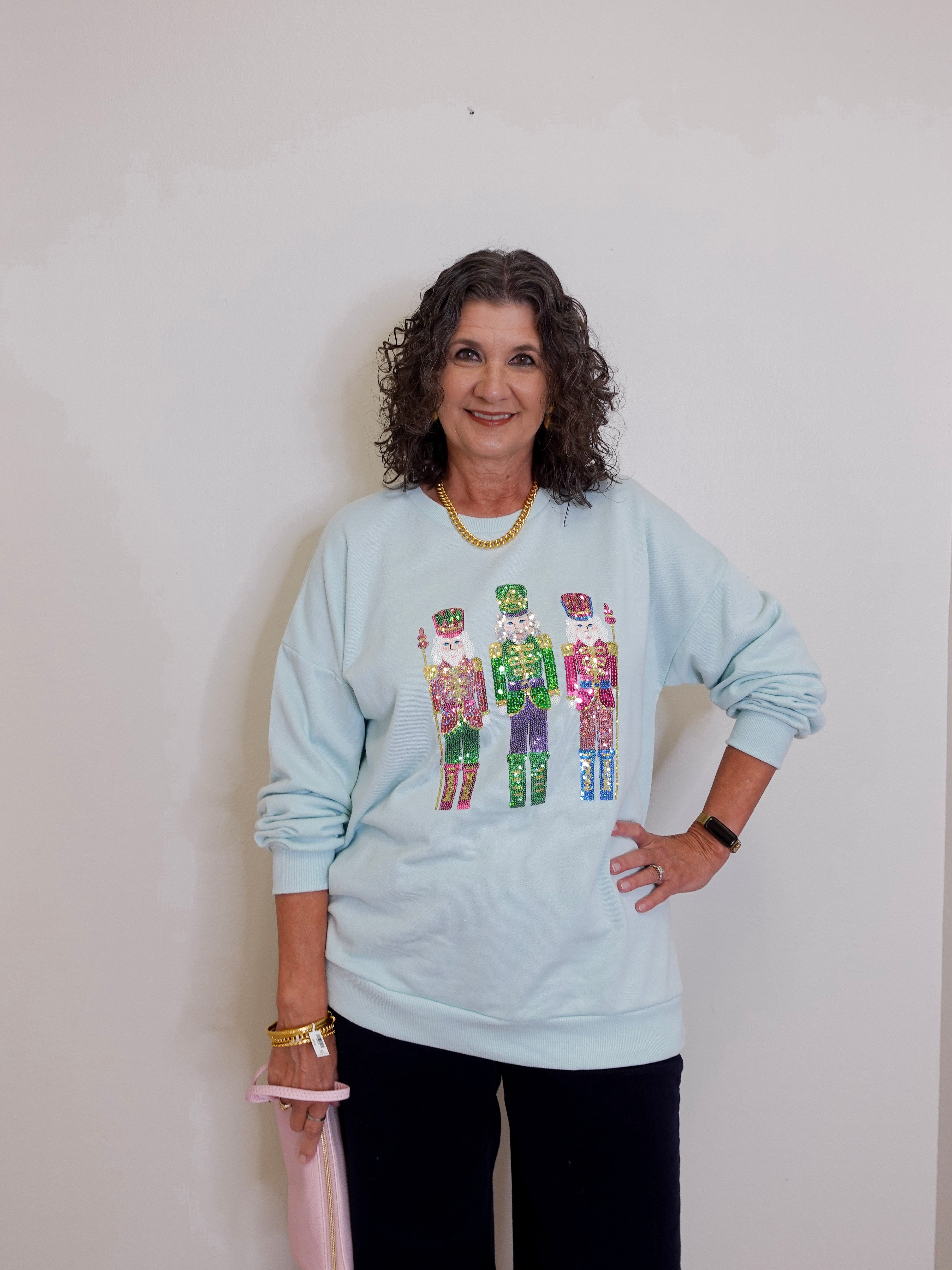 Woman wearing a light blue sweatshirt with colorful designs on a plain background