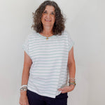 Woman wearing a striped shirt and dark pants against a plain background