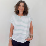 Woman wearing a striped shirt and dark pants against a plain background