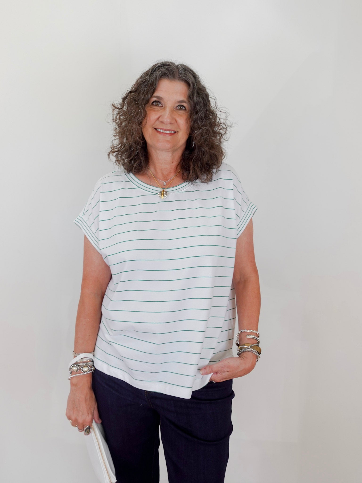 Woman wearing a striped shirt and dark pants against a plain background